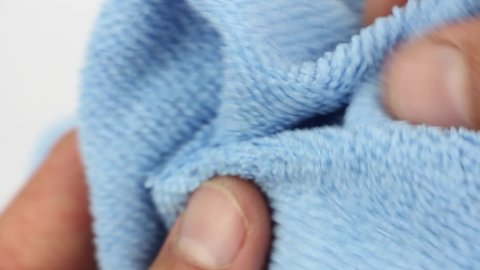 hands testing blue microfiber dusting cloth, well-absorbing water synthetic fabric, close-up view on texture of textile, household cleaning equipment