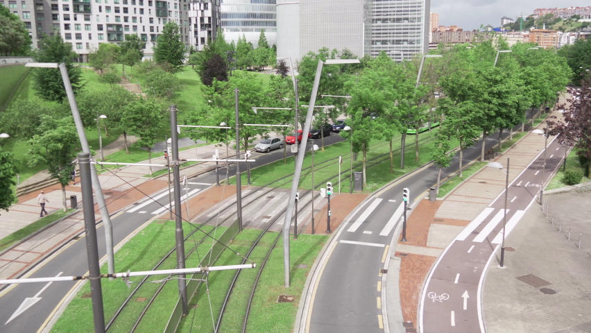 View of the Bilbao tram as it passes through gardens while a bicycle passes along the bike path. Green and sustainable city.  Royalty-Free Stock Footage #1078857650