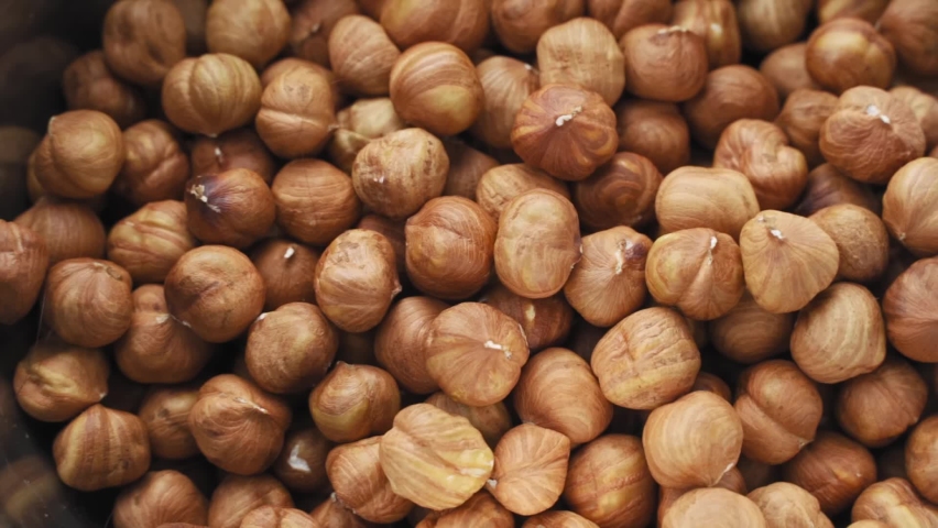 Hazelnuts on a black background. Fresh hazelnut harvest is scattered on a black table. Nuts roll, Hazelnut kernels rotating Royalty-Free Stock Footage #1078862015