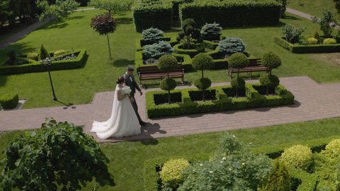 Newlyweds. Lovely caucasian bride groom walking, holding hands in park. Hugging, embracing. Happy wedding couple family. Romantic love of man and woman. Bride in wedding dress. Bridegroom in jacket