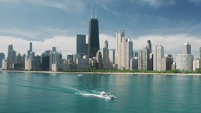 Aerial view of Chicago skyline and white yacht sailing in Michigan lake blue green still waters from downtown Chicago. Water transportation, weekend leisure activity, tourism and summer vacation 4K