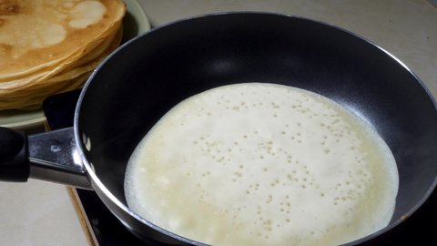 Cooks Pancake Blin on frying pan in home kitchen. Sweet Homemade Food for Breakfast