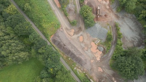 Top down aerial of quarry, tilting up and revealing busy mining site