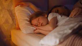 Sleepy mother embraces daughter lying together in bed - Powered by Shutterstock - Get 15% off with code: PIKWIZARD15