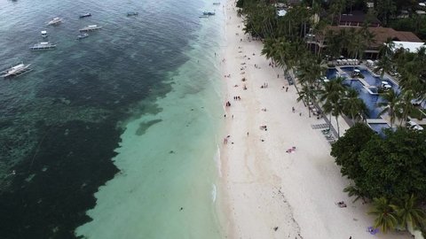 Aerial of Alona beach with blue water, green palm trees, traditional philippine boats and people walking on the seashore, summer and vacation concept, dream trip to island, traveling, sunny summer day