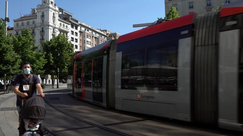Zaragoza, Spain-29 May, 2021: Tram crossing a main street of Zaragoza city with road and trees background. Trams passes through the central area of Saragossa. Spain public transport concept.-Dan