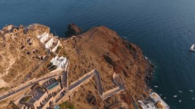 Aerial view of drone on Santorini island, Oia town at sunset, popular romantic place, drone flies over the texture of the volcanic rock of the former volcano