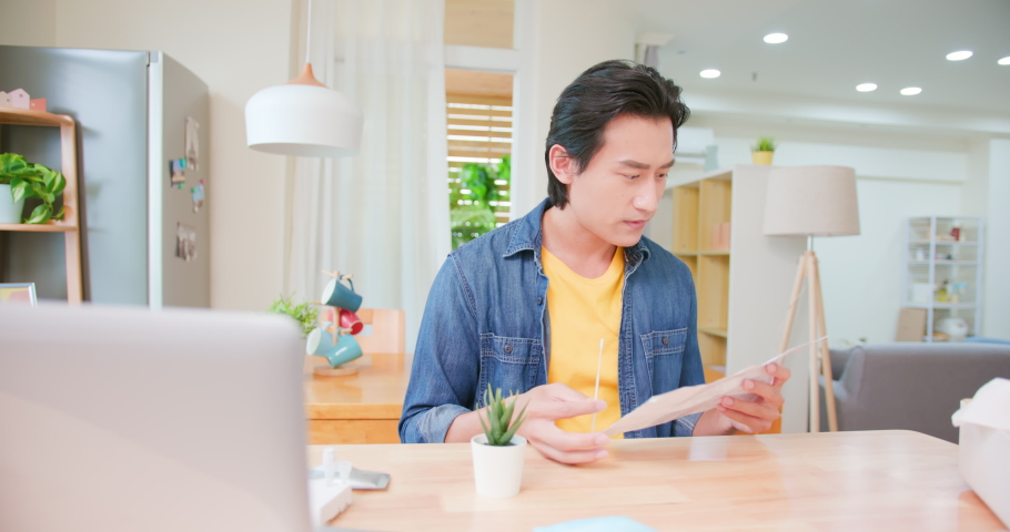 asian man holding a nasal swab is studying the instructions about COVID-19 self test with antigen kit on table at home Royalty-Free Stock Footage #1078886822