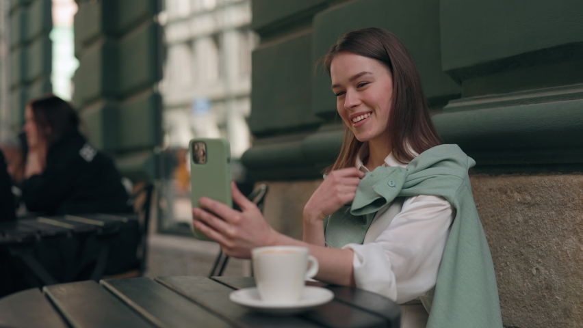 Pretty young woman with hearing loss using cell phone for video call while sitting at cafe terrace. Caucasian brunette telling with sign language phrase I miss you. Modern gadgets for conveniences. | Shutterstock HD Video #1078887536