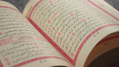Bandung, Indonesia (7-9-2021): Quran (Koran) - close up of holy book of Muslims, with a man's hand turning the page.
