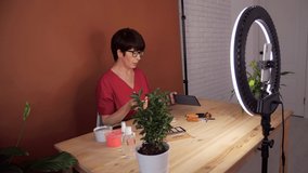 Attractive aged female blogger does make up, reviews beauty product for video blog, gives advice to girls and women, films process on smartphone