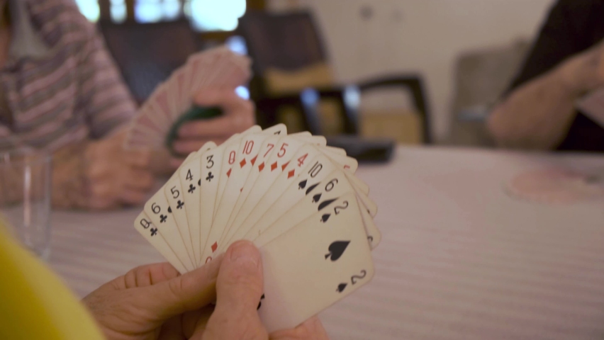 Old people playing cards. retired senior friends at free time playing bridge. fun and playing game of cards. Leisure, recreation, retirement. Over the shoulder view of hands holding Royalty-Free Stock Footage #1078904933