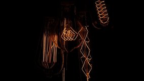 Old lamps on a black background. Several retro lamps turn on and off, pulsing light. Tungsten filaments glow with a warm orange light.