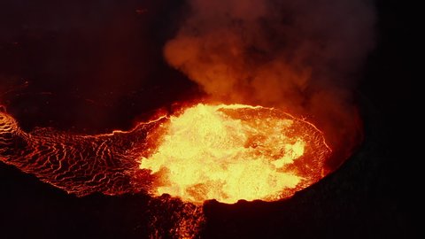 High angle view of hot magma eruption in active volcano crater. Boiling molten material flowing out. Fagradalsfjall volcano. Iceland, 2021