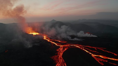 Slide and pan shot of active volcano in before sunrise. Panoramic aerial view of volcanic landscape view glowing hot lava streams. Fagradalsfjall volcano. Iceland, 2021