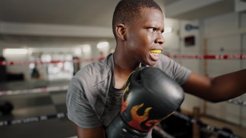 Young tired african male kickboxer during boxing training at gym fight club