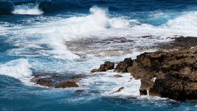 Sea blue water and rocks, Sunny daytime seascape, Devastating and spectacular, ocean waves crash on the rocks of the coast creating an explosion of water