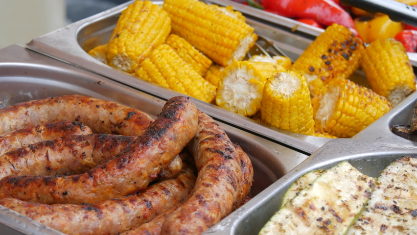 Grilled corn, sausage, eggplant and zucchini counter at outdoor street food festival. BBQ Shop for sale at the food festival. Street food ideas.