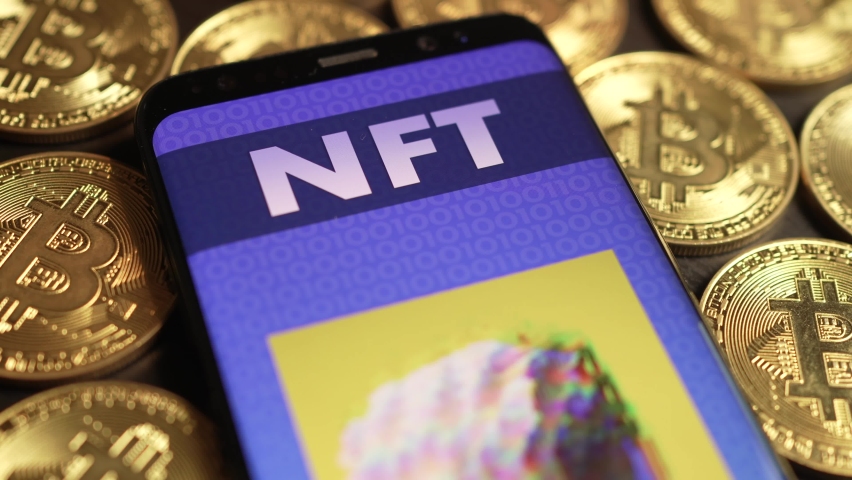 Animated NFT on a smartphone screen sitting on many Bitcoins cryptocurrency coins. Non-fungible token concept Royalty-Free Stock Footage #1078918265