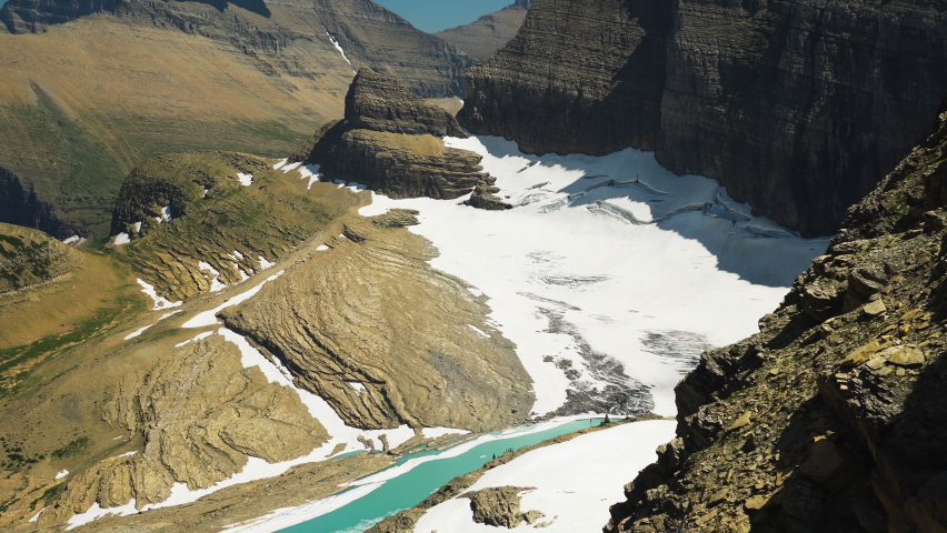 Magical view of sun shining bright through snow capped mountains of national park during winters. Water from melting snow flows through Logans Pass in Glacier National Park.