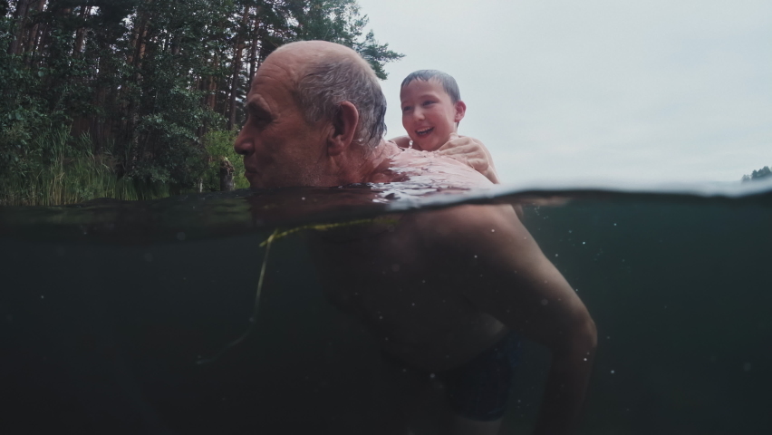 Family swim in lake. Preteen boy swims and has fun in the lake with grandfather. Underwater view of the family jumping and swimming in the lake