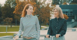 Female colleagues talking, communicating, town street. Outdoor business meeting. Blonde and Redhead woman friends in autumn day, fall style. 4K slow motion video.