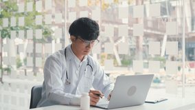 Asian doctor provides online counseling to patients during the virus outbreak keeping a social distance.