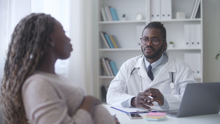 Black male gynecologist talking with happy pregnant woman at clinic, healthcare | Shutterstock HD Video #1078933967