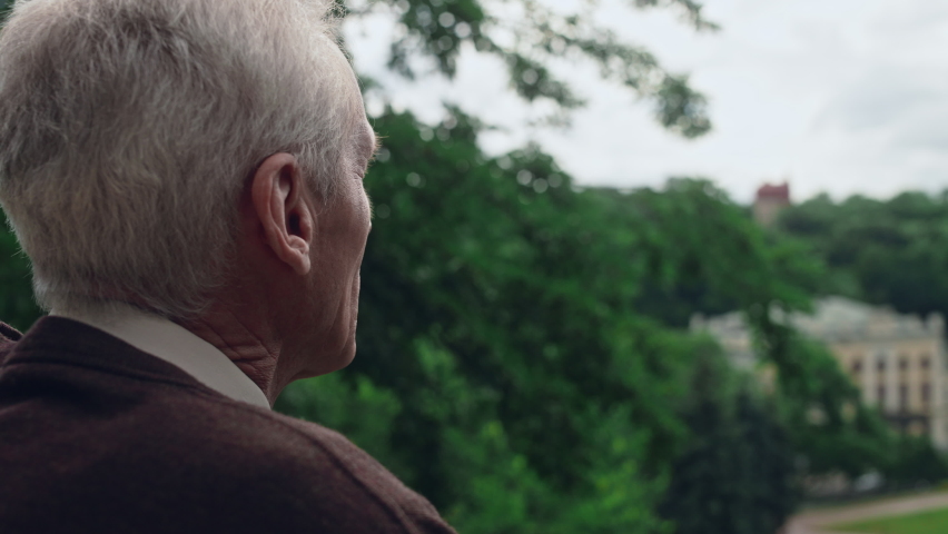 Upset senior man looking at picturesque landscape from elderly home balcony