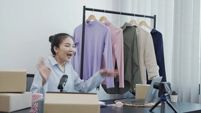 Young asian entrepreneurs are picking up their clothes to show off to customers through online sales on a live phone.