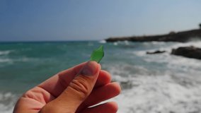 video A shard of glass in a male hand against the background of the blue sea and waves, a blue sky and sun. The concept of summer vacation, relaxation and meditation. Island Cyprus.