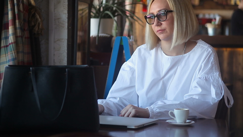 The woman finished typing on her laptop and taking off glases, take coffee