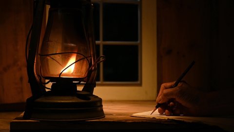 man hand writing in kerosene lamp light