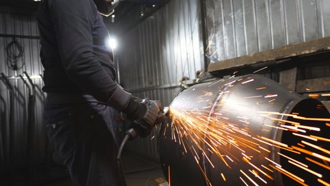 Man use saw cutting machine to cut metal detail. Unrecognizable guy with circular saw hard worked over the steel in garage. Industrial professional worker grinding metal. Sparks fly from hot metal