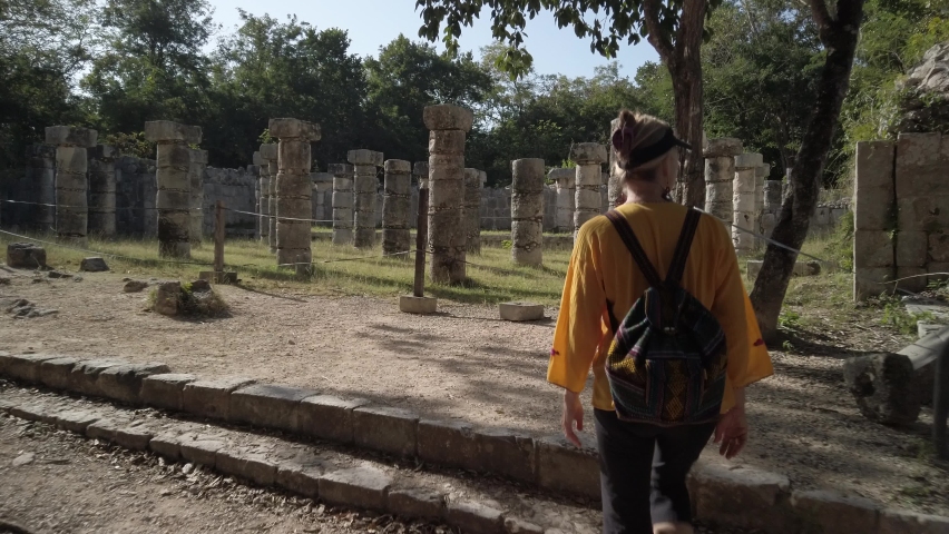 Mature blond woman walks among the ruins at Chichen Itza historical park in Yucatan, Mexico.