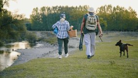 Slow motion: Tourist senior couple  walking in nature with a dog. Hiker traveler old man in hat with backpack hiking in nature. bio-tourism. Following Back View Shot - Powered by Shutterstock - Get 15% off with code: PIKWIZARD15