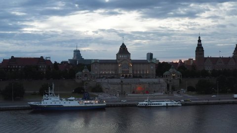 Ferry Services Docked On The Side Of Oder River At Twilight With National Museum Of Szczecin In Background. Chrobry Embankment In Poland. wide drone shot