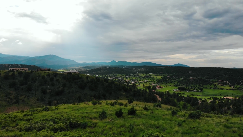 Aerial flyover rural landscape with New Mexico Valley in background during cloudy day - Near Alto Lake,US