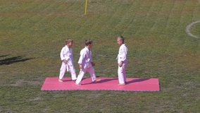 Three athletes in karategi bully tatami throws at the stadium