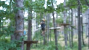 Unidentified man on a course in adventure park. Blur and out of focus done intentionally. Background video. Male climber rope park, outdoor activity training.