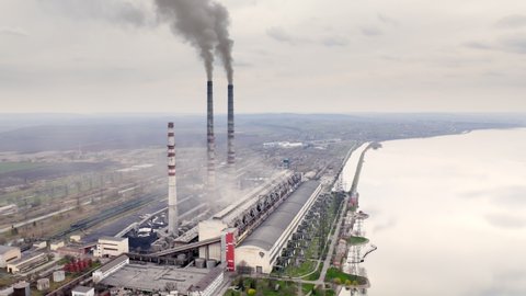 Aerial view of a power plant generating electricity and useful heat. Grey steam exits out of high pipes at the outskirts of a city. High quality 4k footage
