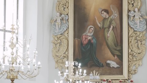 Derevnoe, Belarus - October 27 2017: Painting of Annunciation of Virgin Mary. Angel came to Mother of God with good news, dove hovers over woman. Icon hangs on wall in church with statues of angels.