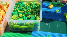 Close-up view 4k video footage of many children playing construction plastic blocks toys outdoors on sunny summer day