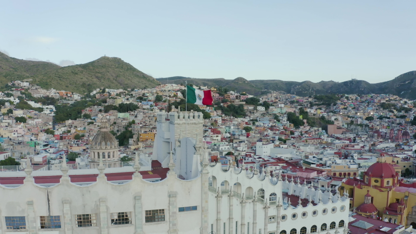 Panoramic aerial view of the huge Central Building of the University of Guanajuato surrounded by colorful houses with a beautiful sunset in the background