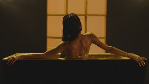 Beautiful, thin and sexy woman on bikini lying inside bathtub in luxury designed bathroom interior . Girl with long legs having bath moving and dancing . Side view slow motion . Sexual performance