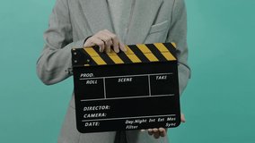 Movie slate or clapperboard hitting. Business woman holding empty film slate and clapping it. yellow and black clapper board isolated on blue green background. video film production.