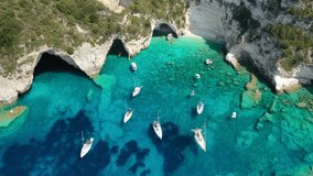 Aerial drone video of sail boats and yachts anchored in tropical Caribbean island paradise bay with white rock caves and turquoise clear sea