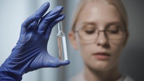 A female doctor with glasses holds an ampoule in her hand and brings an albino experimental mouse to it. The white mouse reaches for the vaccine with its small paws. - Powered by Shutterstock - Get 15% off with code: PIKWIZARD15