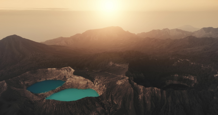 Orange sunset over Kelimutu blue crater lake. Panorama aerial view of sun dawn over volcanic mount in Indonesia. Nature background. Travel destination. Beautiful wild landscape. Exotic summer vacation