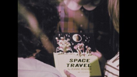 1970s: Child in library holds book on space travel. Rocket launches from pad. Three children look at book in library. Books on shelf in library.